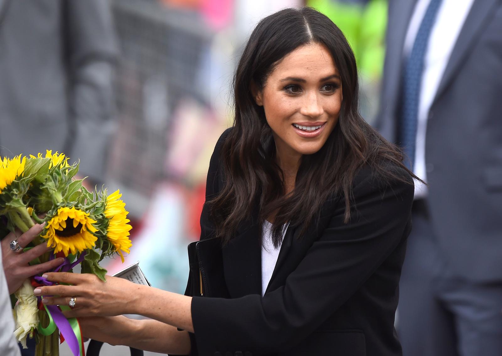 Britain’s Meghan, the Duchess of Sussex, accepts some flowers during a visit to Parliament Square in Trinity College, Dublin