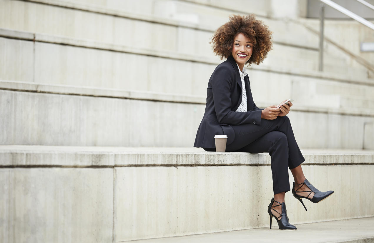 Happy businesswoman holding smart phone on steps
