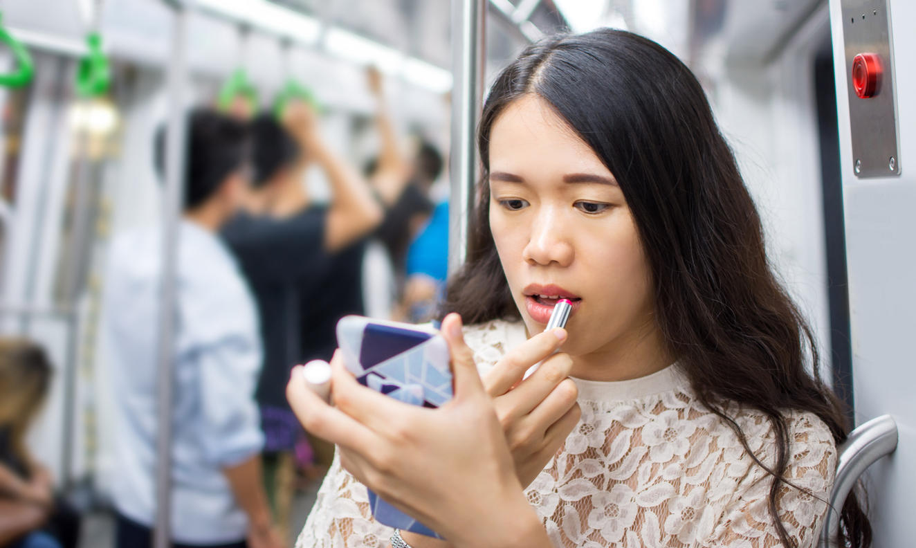 Asian girl fixing make up on subway