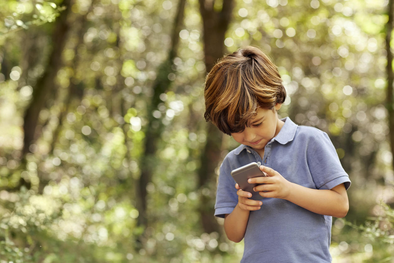 Smiling boy using mobile phone in forest