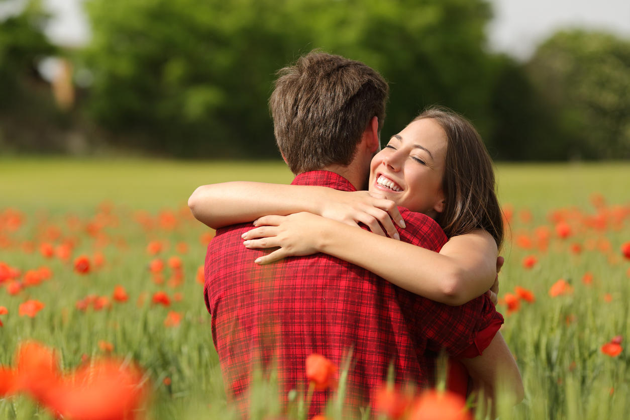 Couple hugging after proposal in a flower field