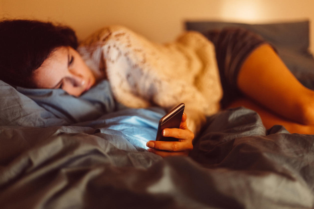 Low-spirited woman in bed text messaging