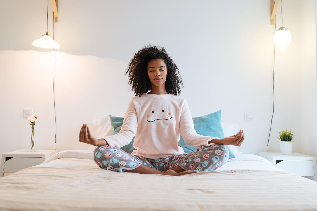 Happy beautiful young black woman relaxed  at home doing morning meditation in bed “n