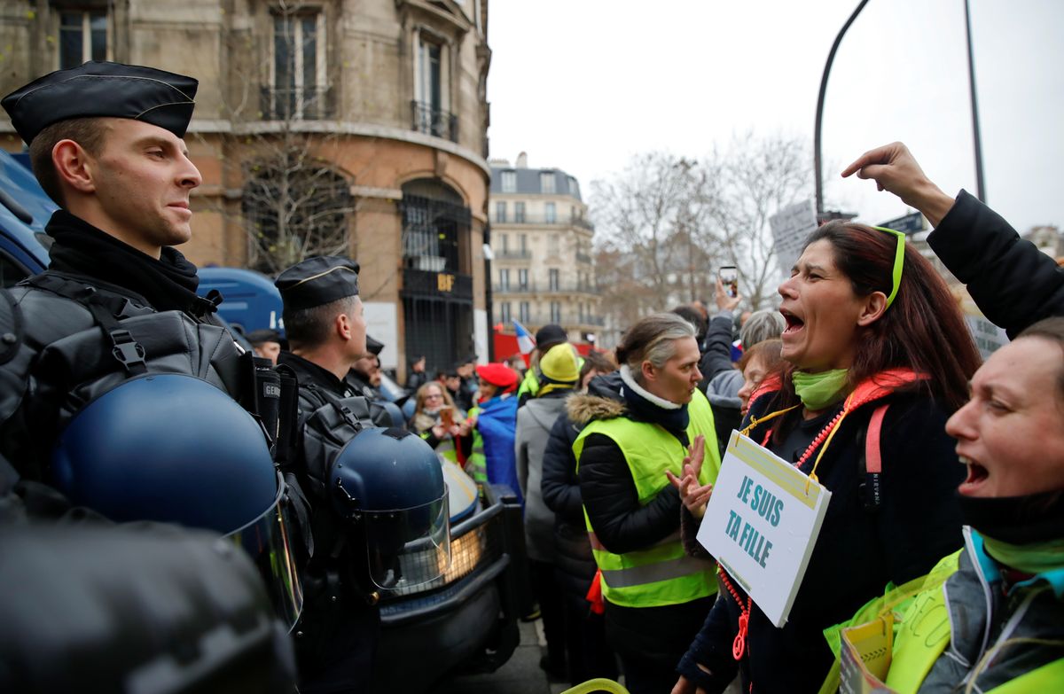 Protesters wearing yellow vests face police as they take part in a demonstration by the “Women’s yellow vests” movement in Paris