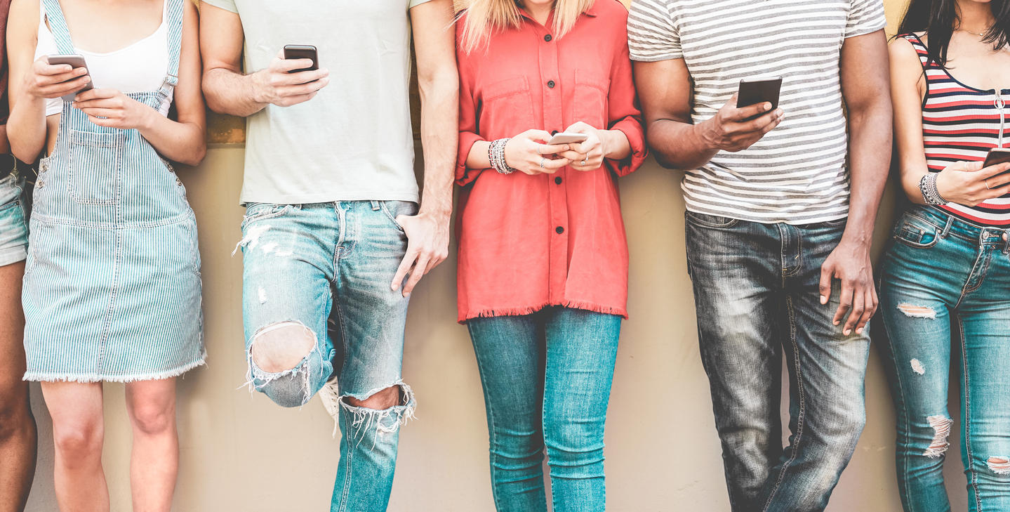 Group of millennial friends watching smart mobile phones – Teenagers addiction to new technology trends – Concept of youth, tech, social and friendship – Focus on smartphones