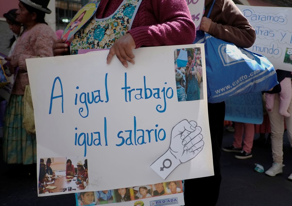 A woman holds a sign reading: “same job, same salary” during a rally in the Women’s Day celebration in La Paz