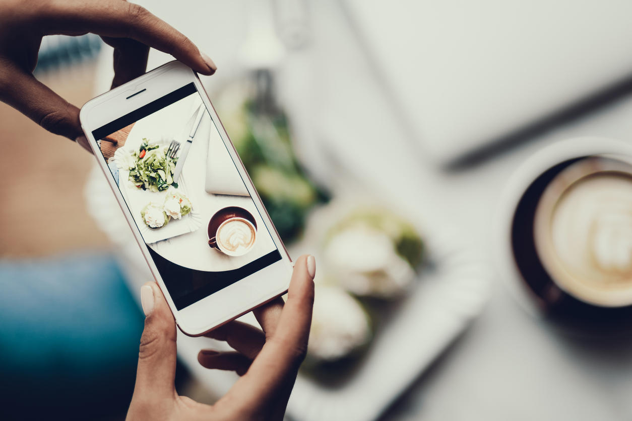 Woman holding cellular in hands and taking picture of her food