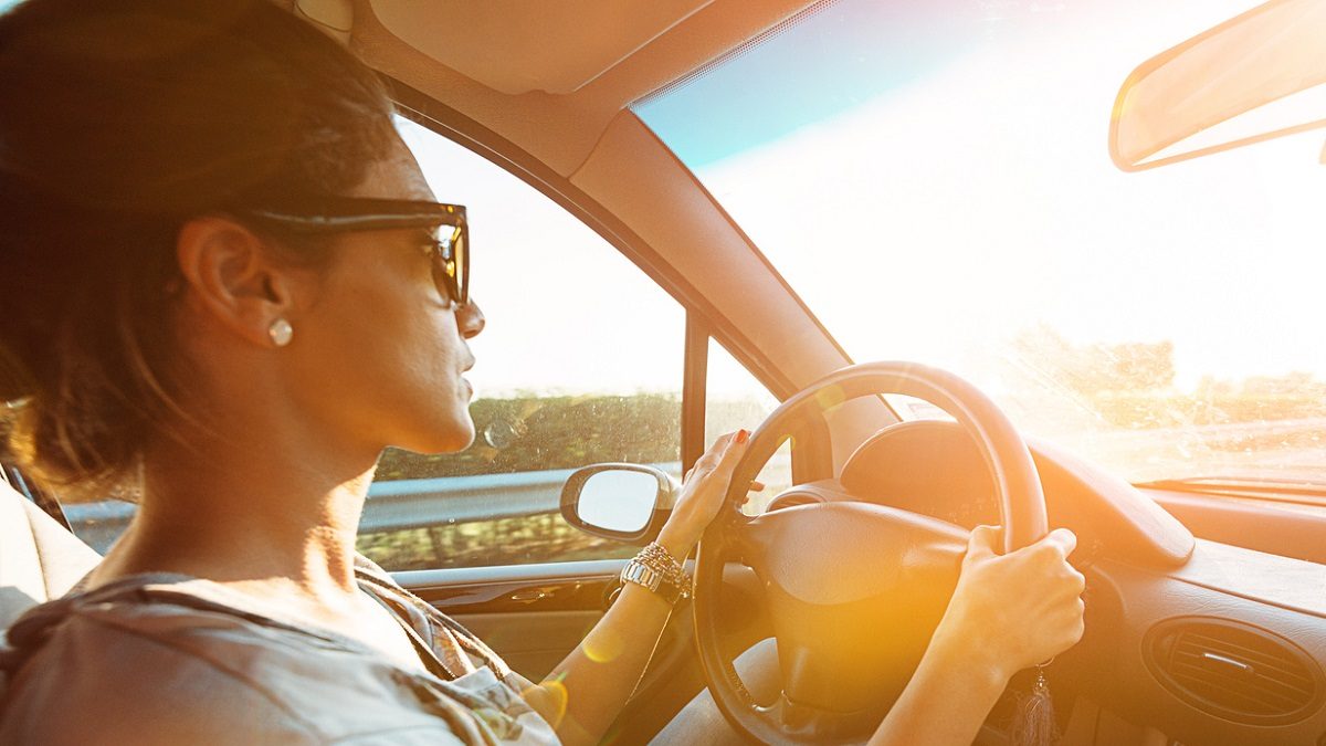 Young woman driving car and speeding on highway in summer