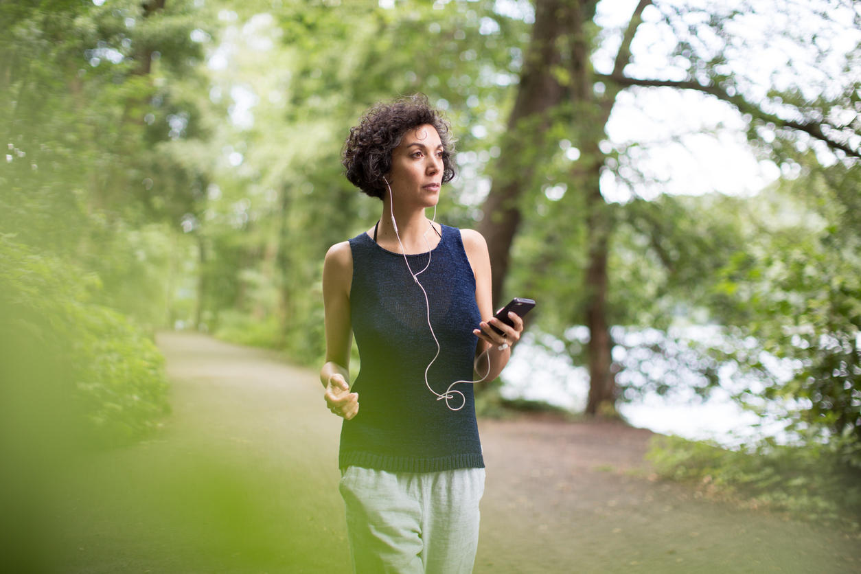 Woman listening to music while walking in forest
