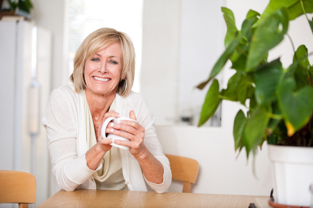 Cheerful middle aged woman enjoying hot tea