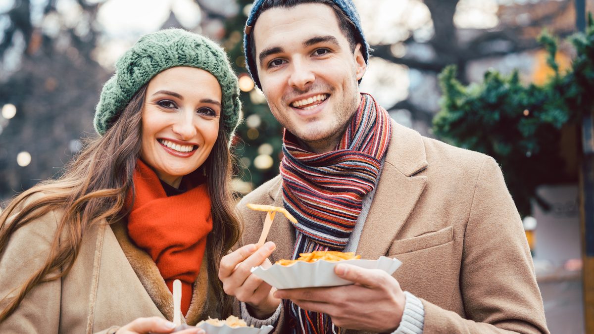 Man and woman eating snacks on a Christmas Market