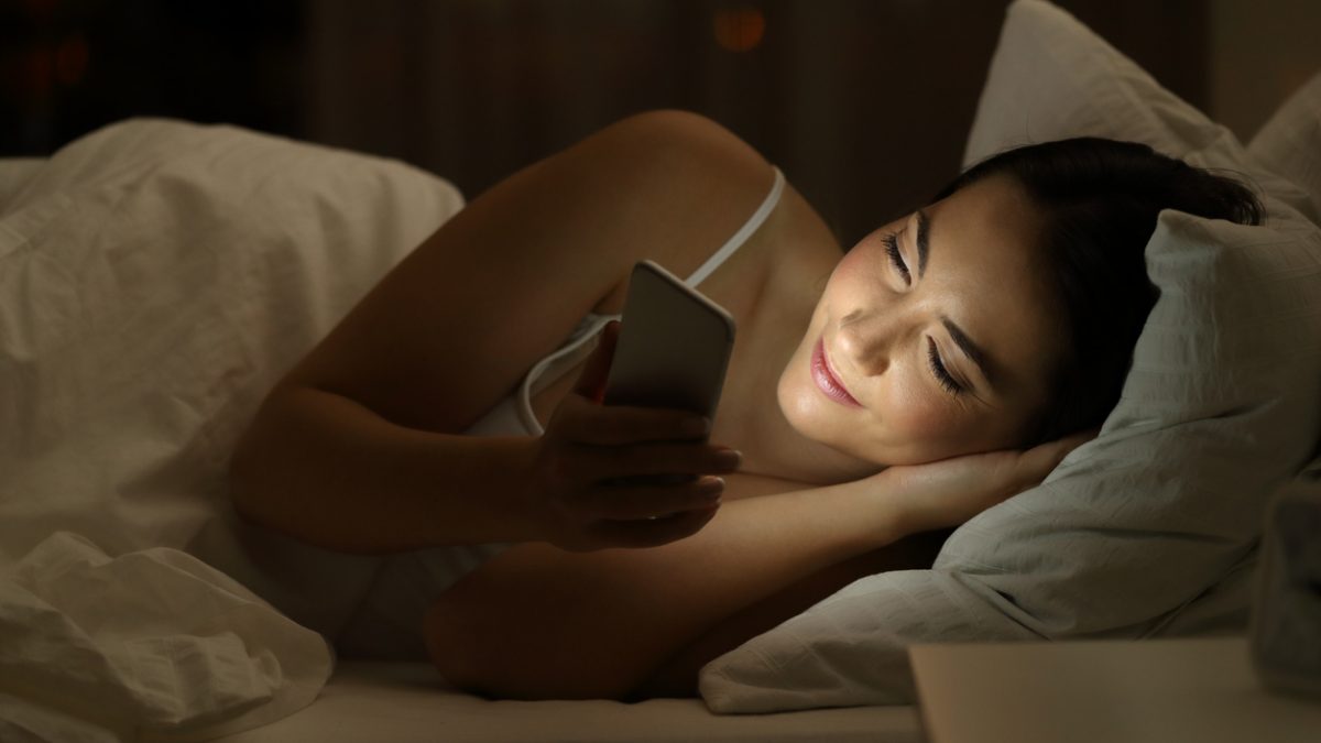 Girl using a smart phone on the bed in the night