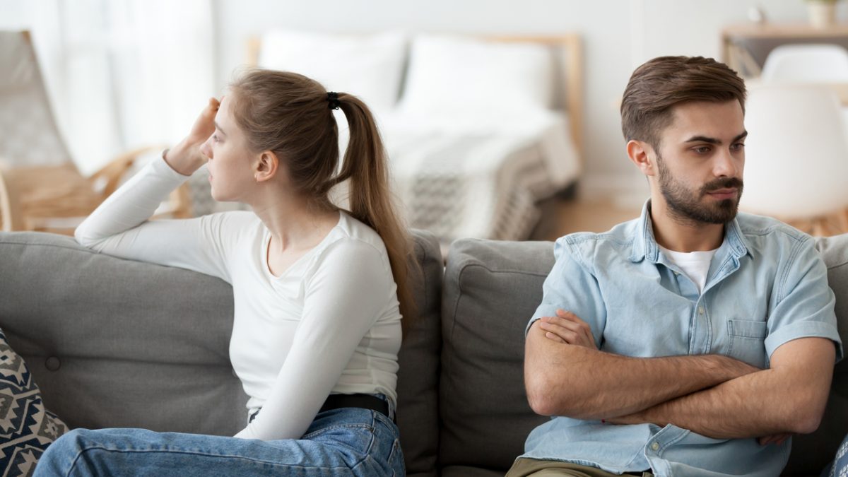 Man and woman sit separately on couch after fight