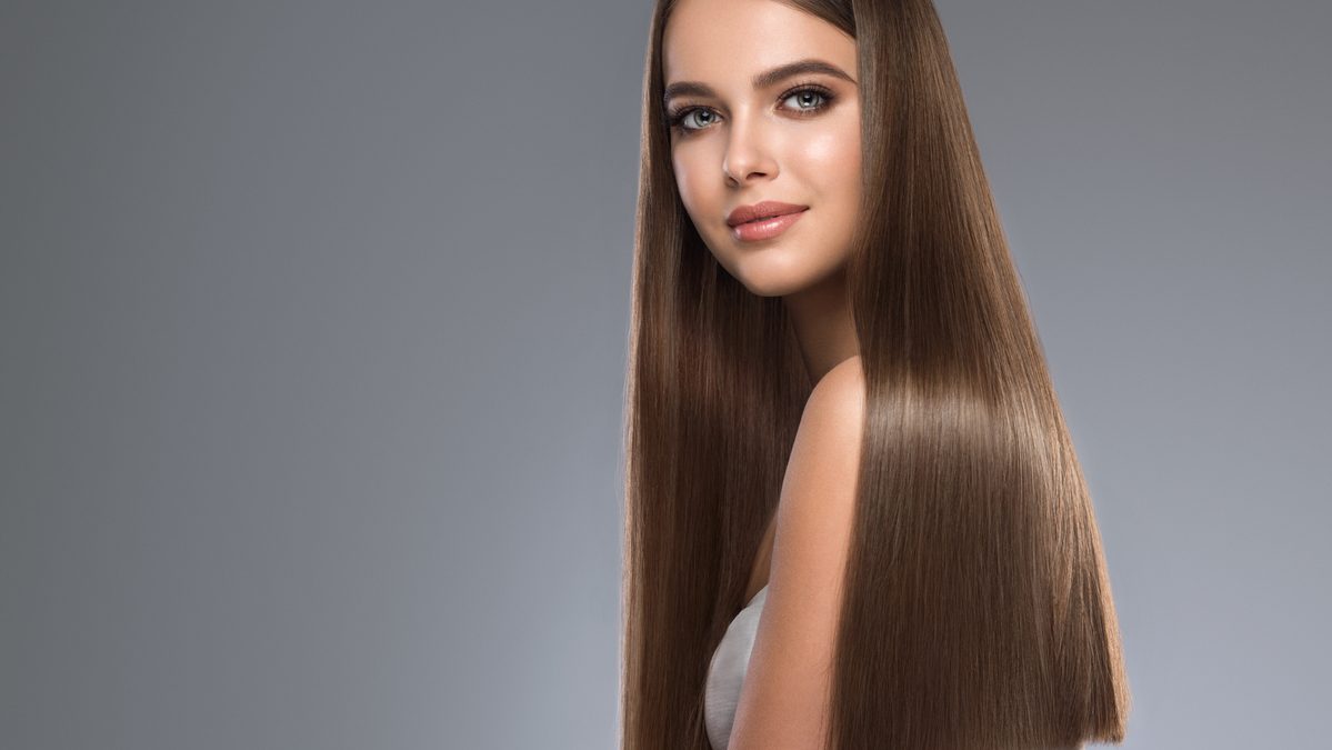 Young, brown haired beautiful model with long,  straight, well groomed hair. Hair care and hairdressing art.