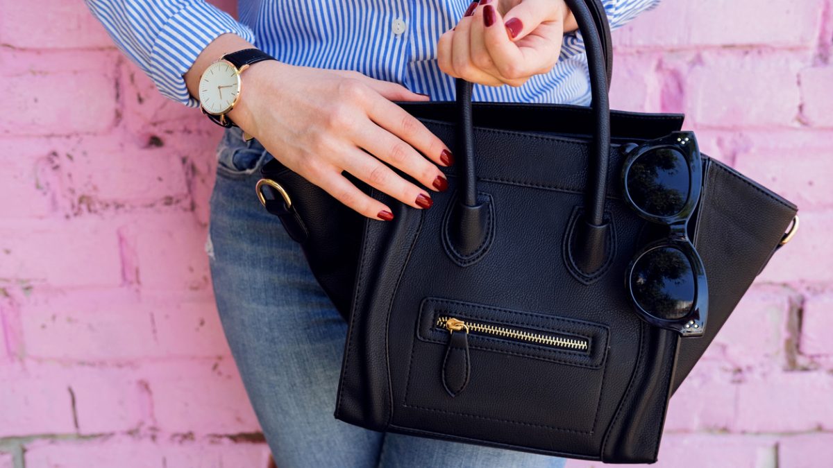 Close up black leather bag in hand of fashion woman.