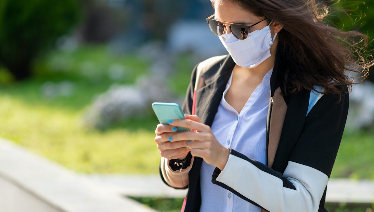 Woman with protective face mask texting on mobile phone