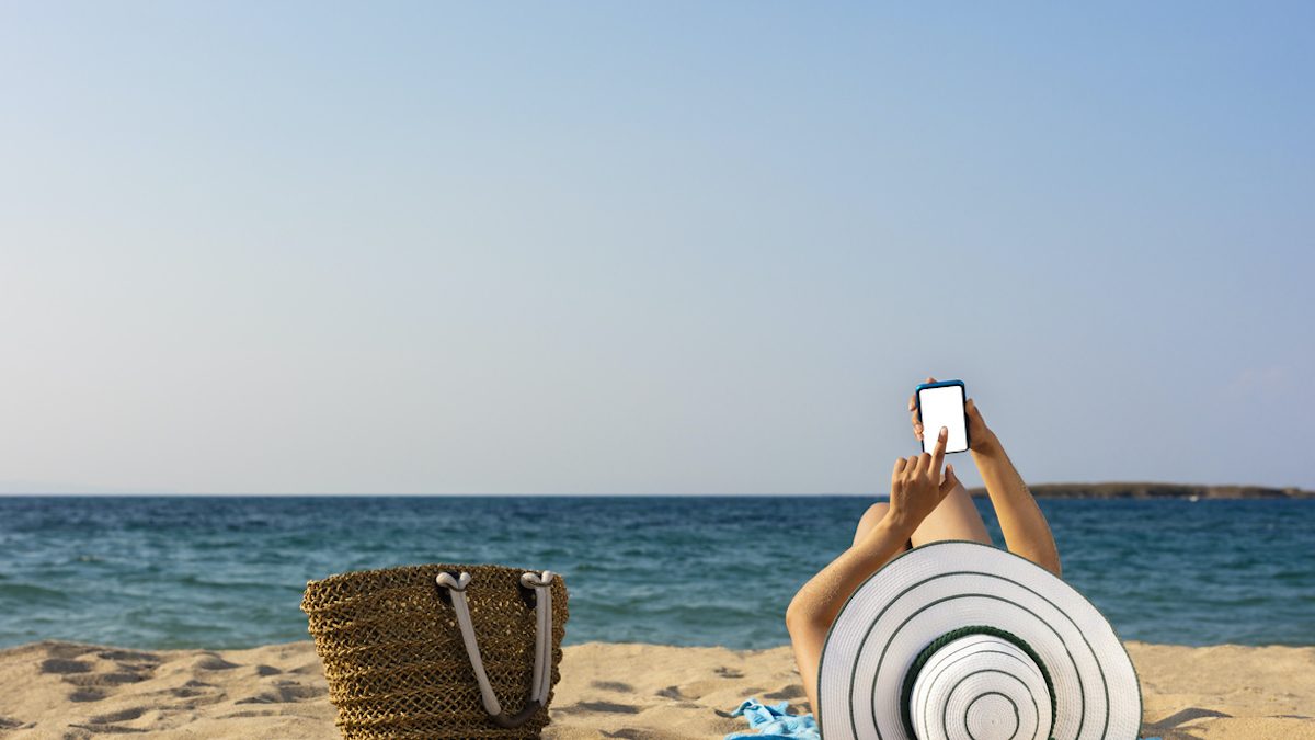 woman with smartphone on beach