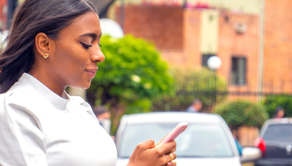 Woman waiting a car ride with cellphone in street
